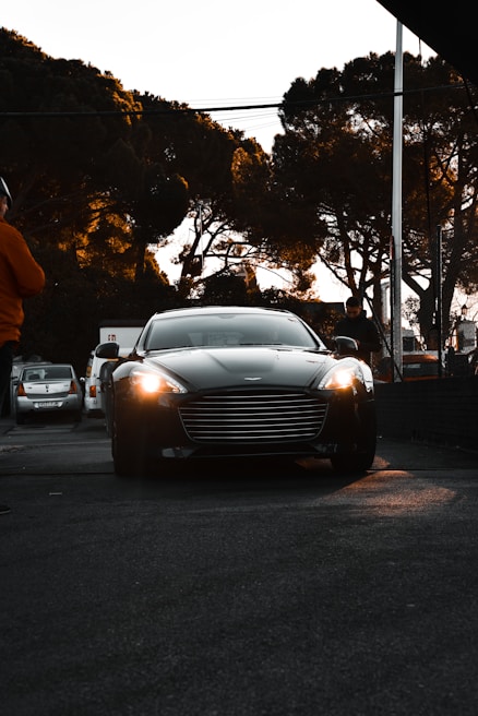 A shiny luxury sedan with tinted windows, parked on a city street at dusk.