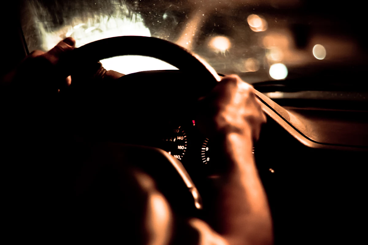 Two hands on a steering wheel at night
