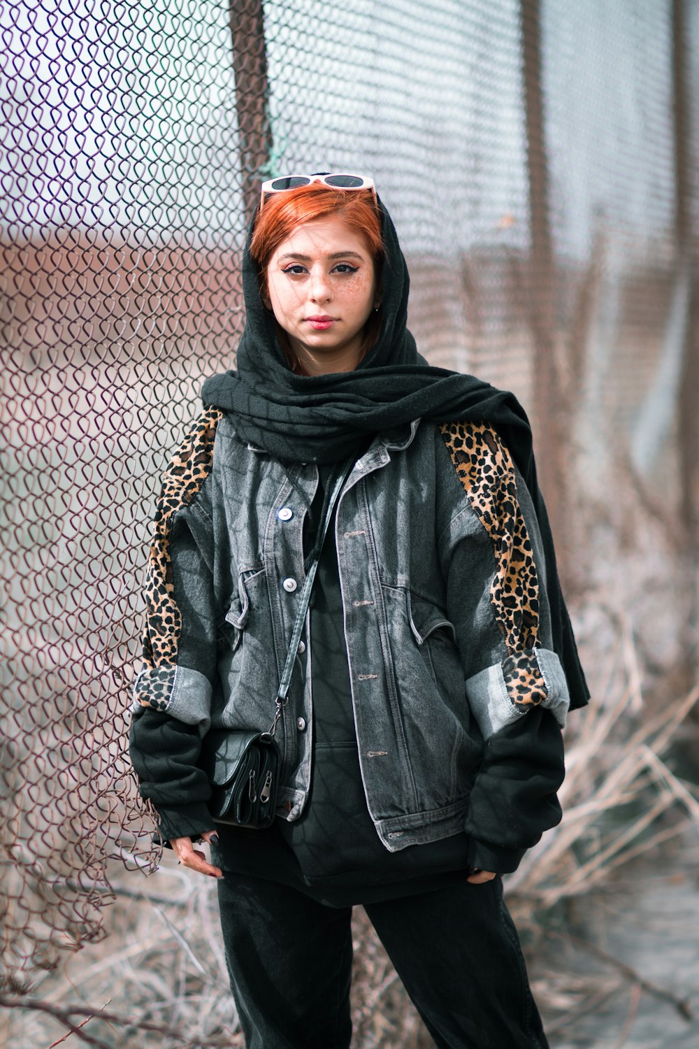 woman in black leather jacket standing beside chain link fence