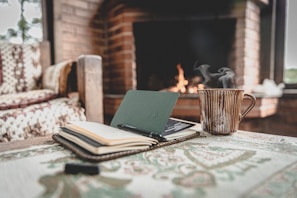 A cozy corner with a steaming mug, notebook, and a glowing forge rust-colored lamp.