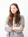 woman in gray cardigan and black and white striped dress