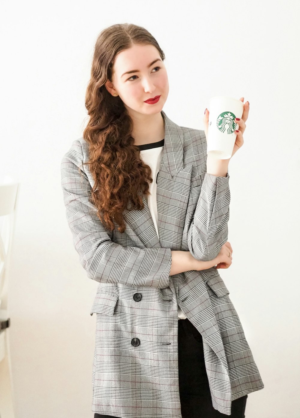 woman in gray coat holding white ceramic mug