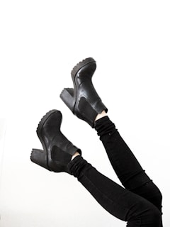 person wearing black leather boots