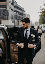 man in black suit jacket and black pants sitting on black car