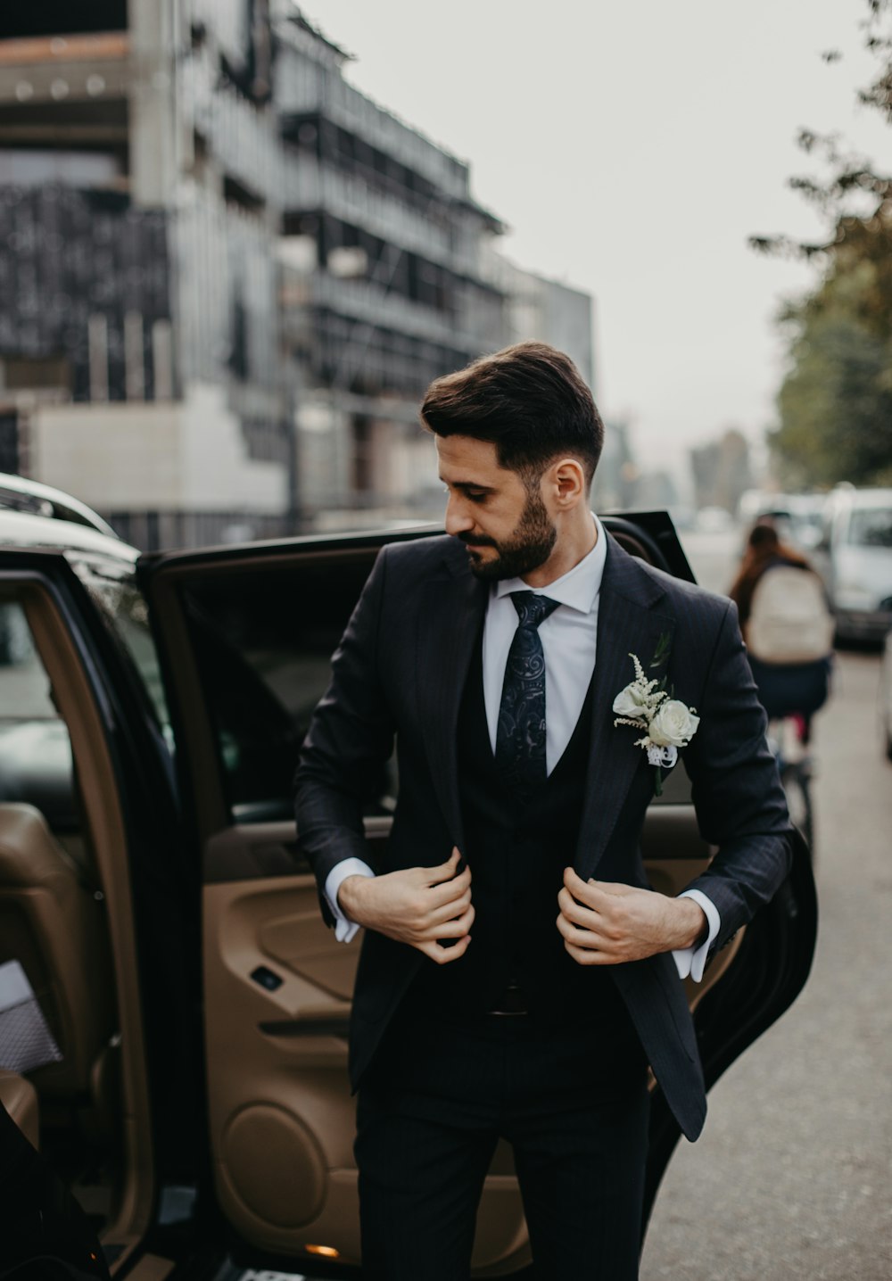 man in black suit jacket and black pants sitting on black car