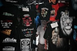 A variety of T-shirts are displayed with humorous and bold text designs, featuring phrases like 'I don't need Google,' and graphics such as lions and tigers. The T-shirts are predominantly dark with bright text and images.