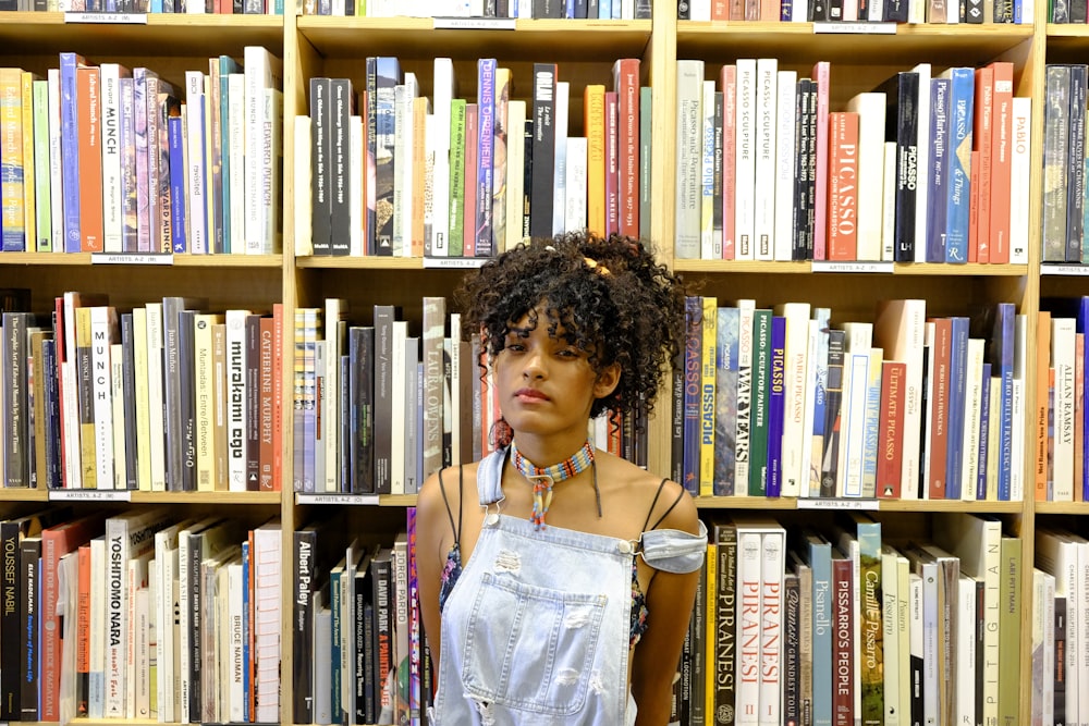 woman in blue denim vest standing near books