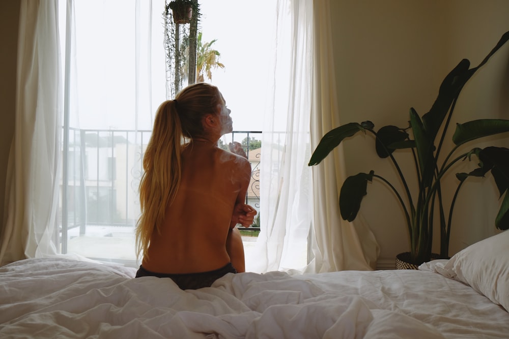 Frau in orangefarbenem Tanktop und schwarzem Rock sitzt auf dem Bett