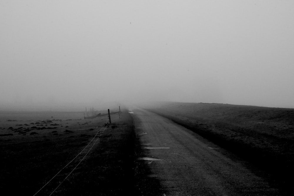 grayscale photo of road in the middle of the field