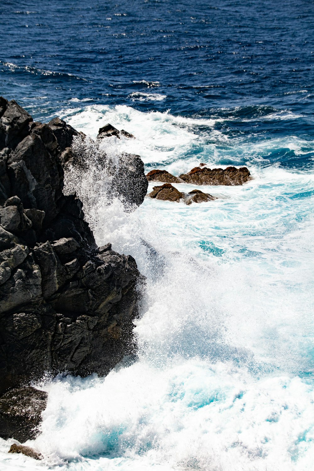 ocean waves crashing on rocky shore during daytime