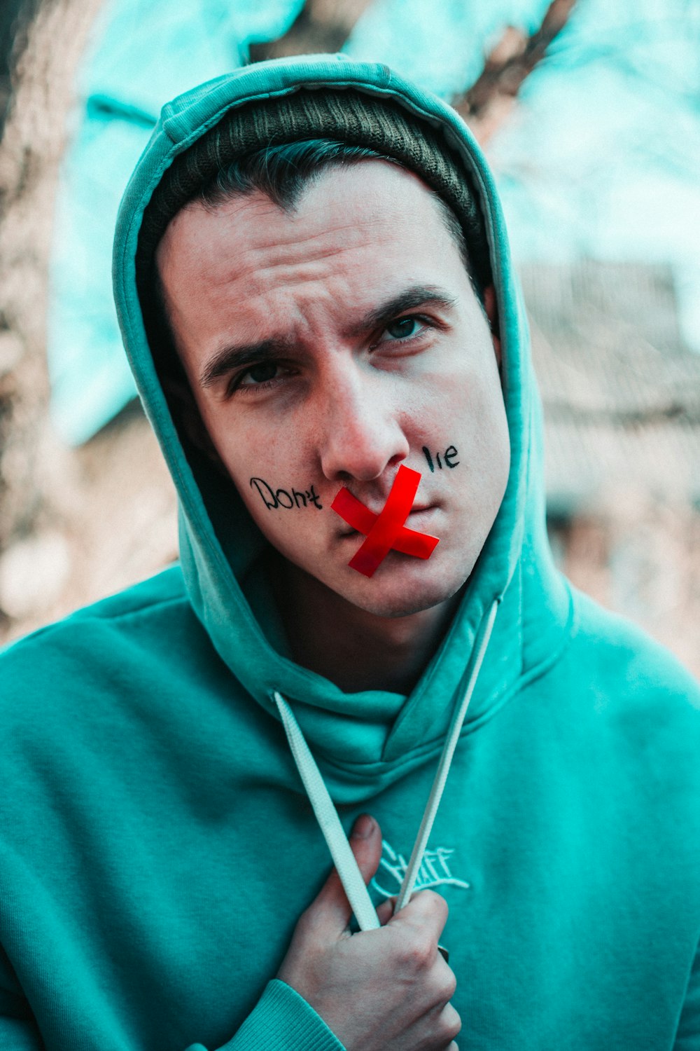 man in blue hoodie with red cross on his head