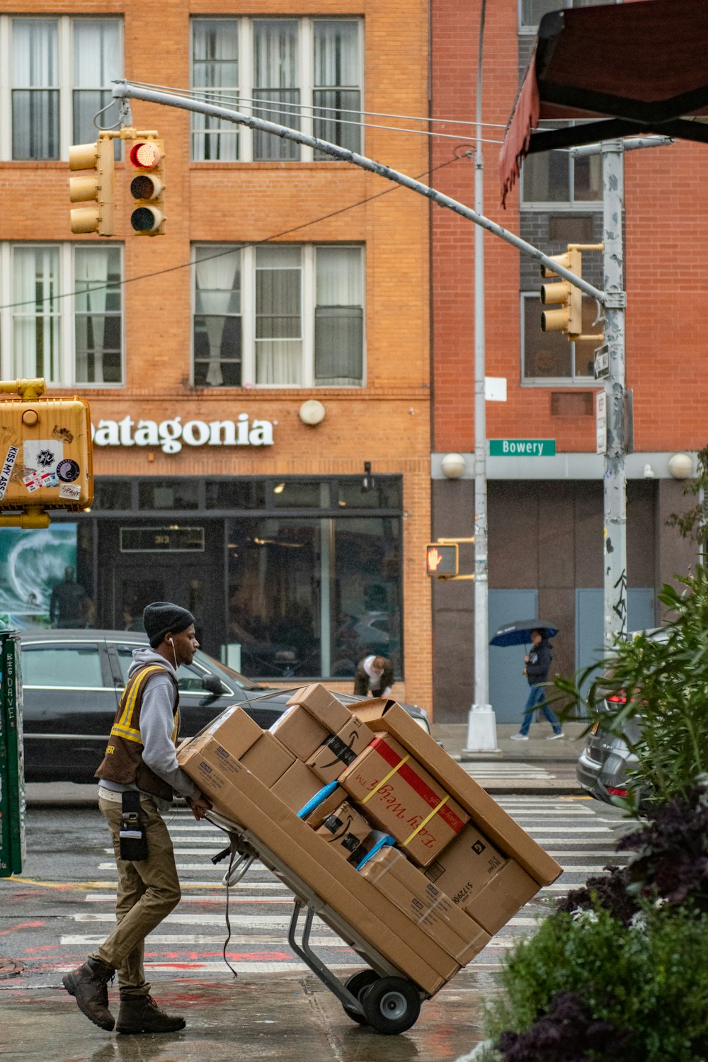 man in green jacket and black pants standing in front of brown building during daytime