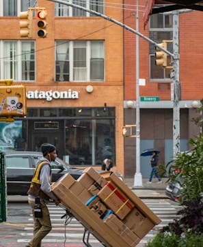 man in green jacket and black pants standing in front of brown building during daytime