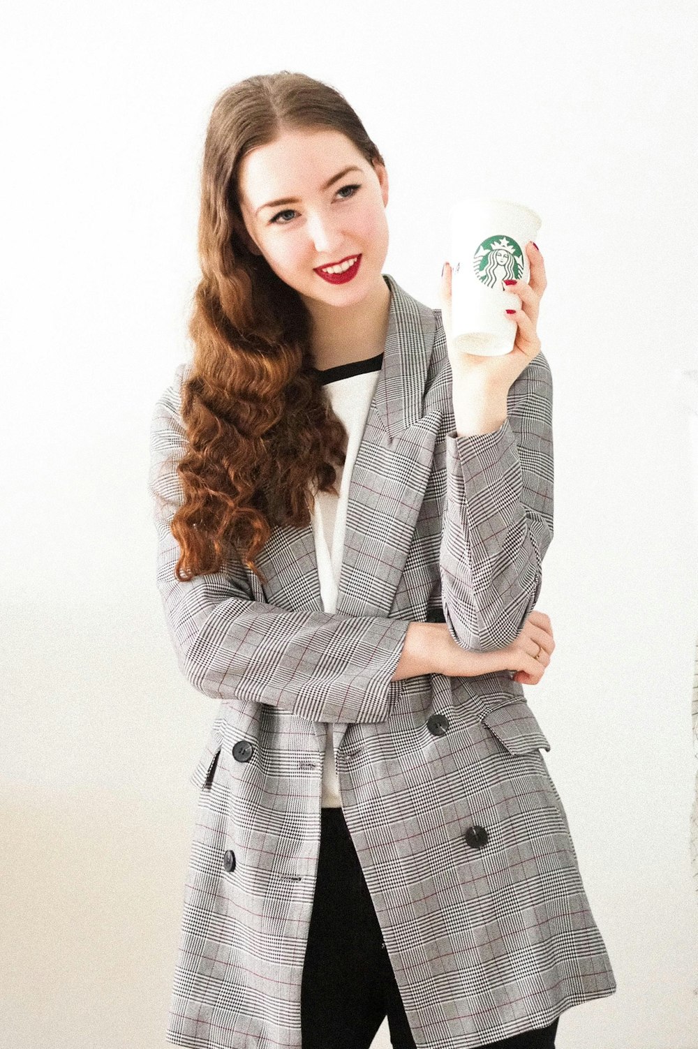 woman in gray blazer holding white ceramic mug