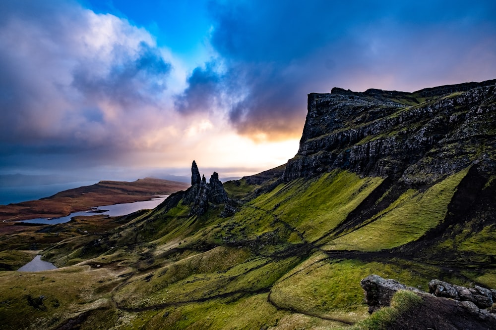 green grass covered mountain under cloudy sky during daytime