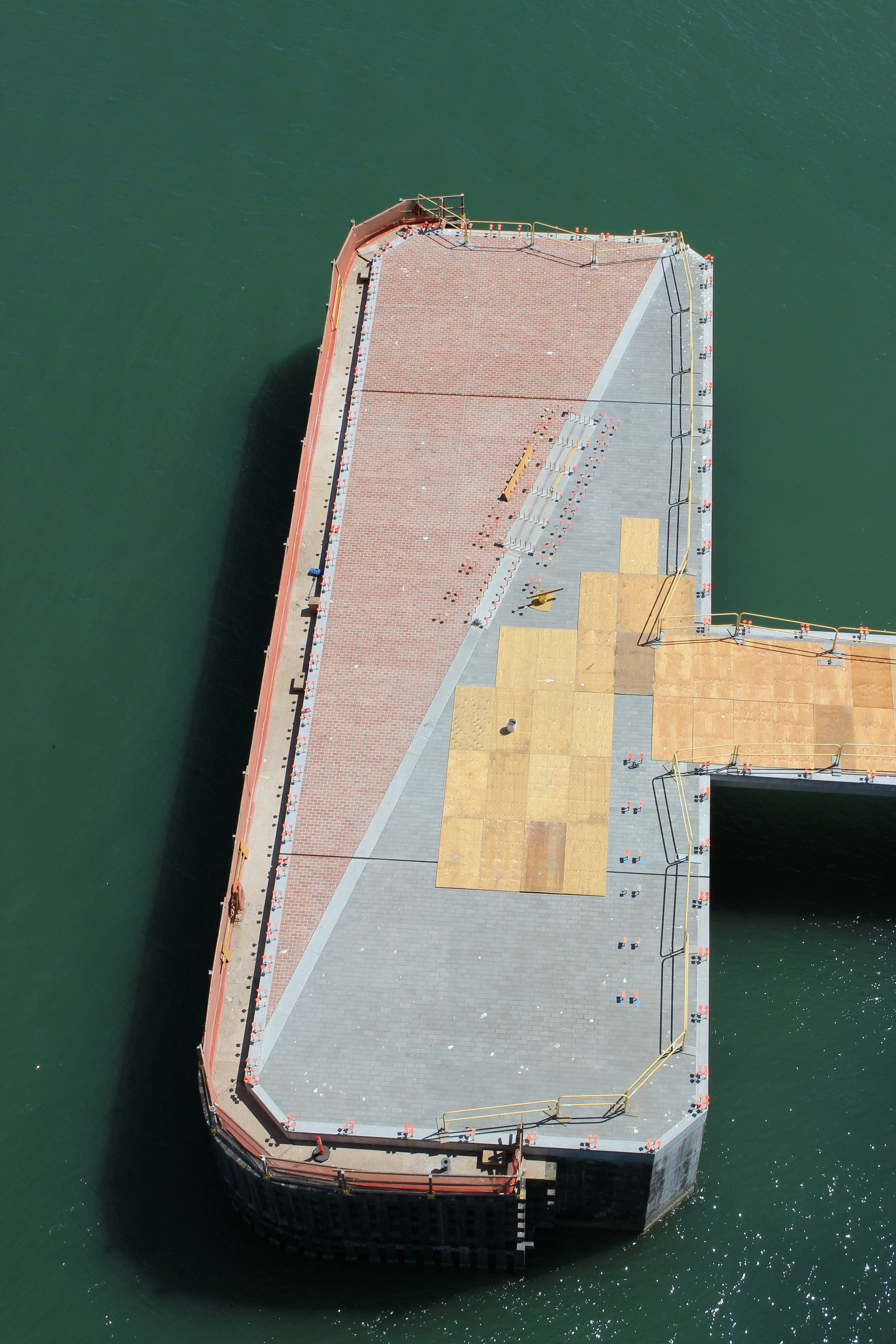 aerial view of brown and gray concrete building beside green body of water during daytime