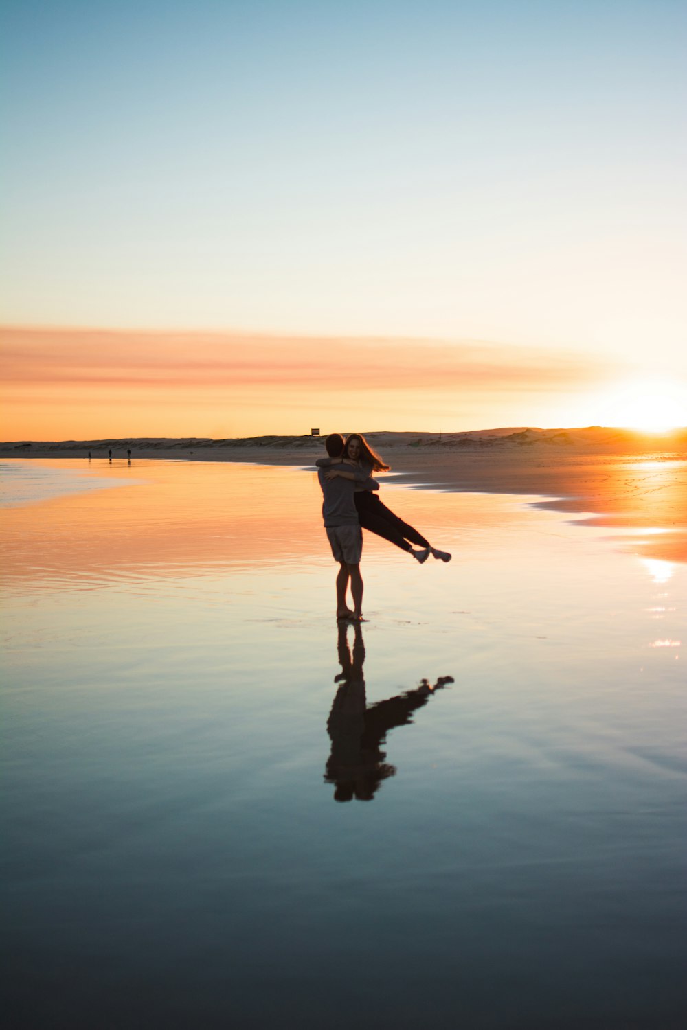 man in black jacket and pants standing on shore during sunset