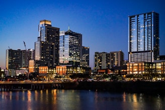 A modern Bangalore skyline at dusk with warm lights glowing from residential and commercial buildings.