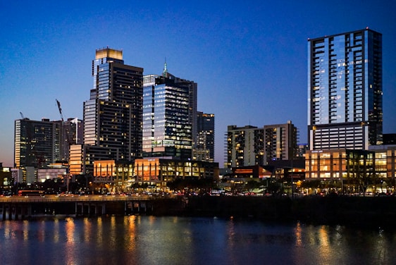 A modern Bangalore skyline at dusk with warm lights glowing from residential and commercial buildings.