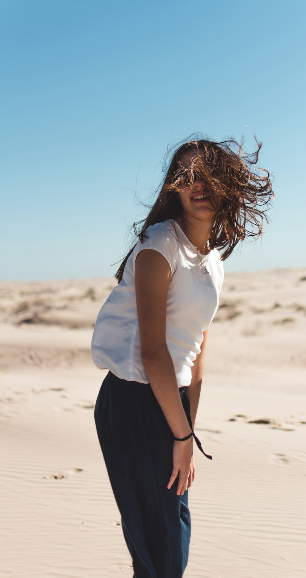 woman in white shirt and black skirt standing on brown sand during daytime