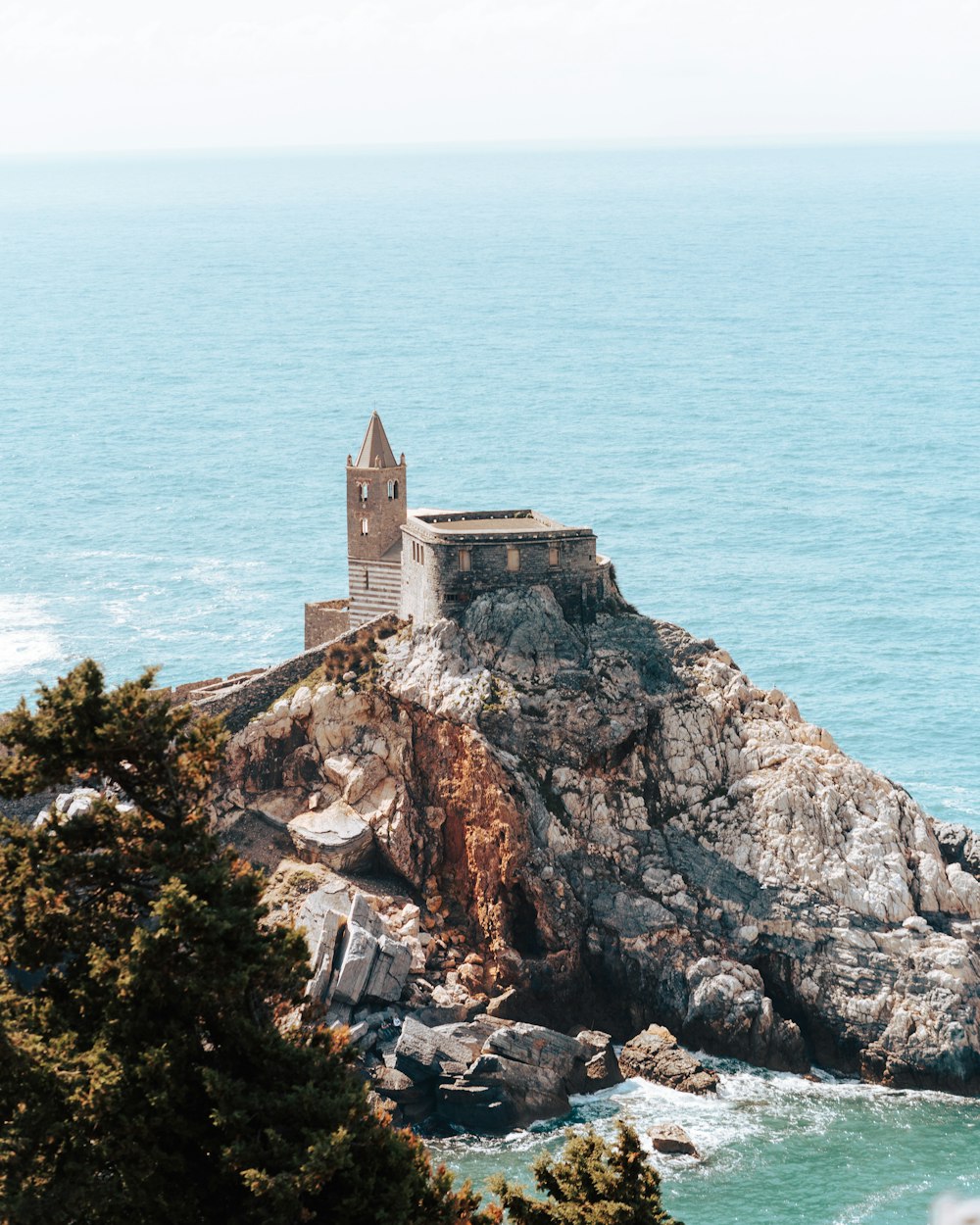 brown concrete building on cliff by the sea during daytime