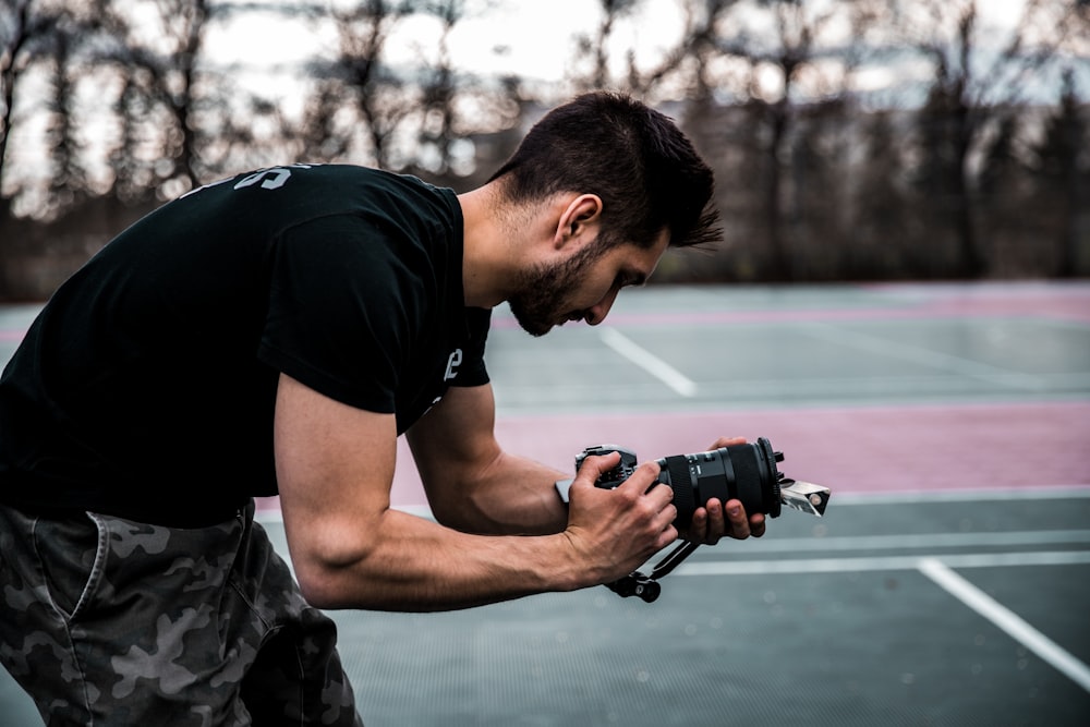 man in black crew neck t-shirt holding black dslr camera