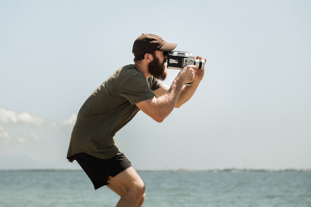 man in brown t-shirt and black shorts holding camera