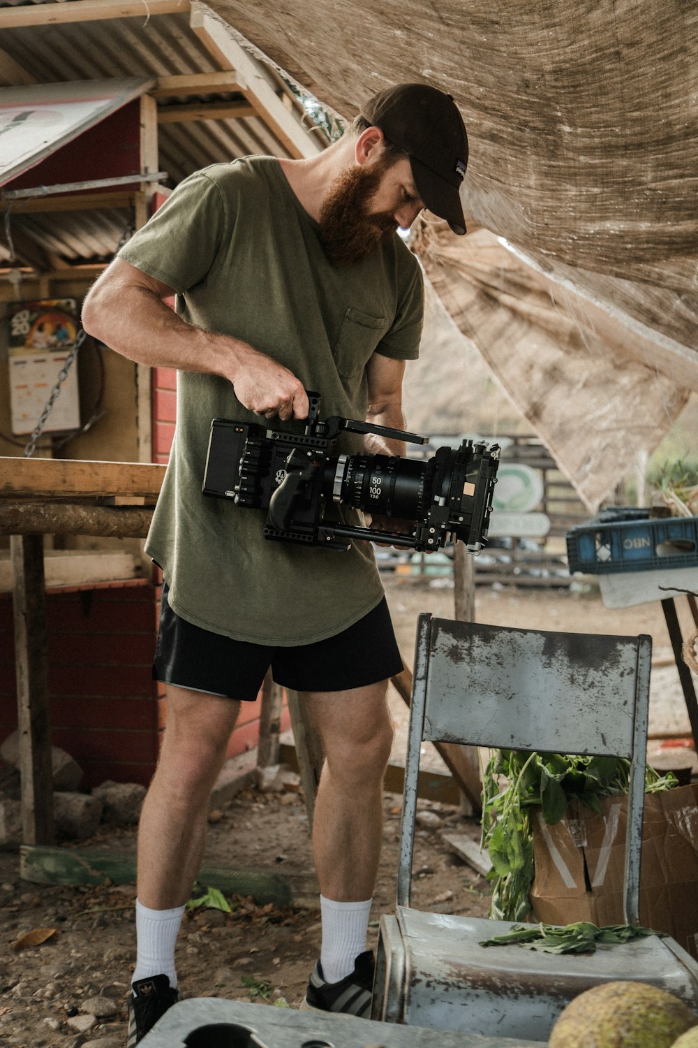 man in green t-shirt and black shorts holding black dslr camera