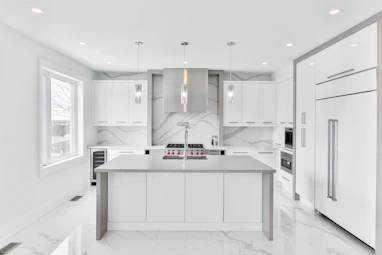 A sleek kitchen space featuring minimalist cabinetry and elegant marble countertops.