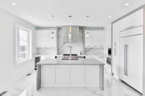 A bright, modern kitchen featuring sleek cabinetry and a large island with marble countertops.