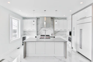 A sleek, modern kitchen featuring dark cabinetry, marble countertops, and ambient lighting.