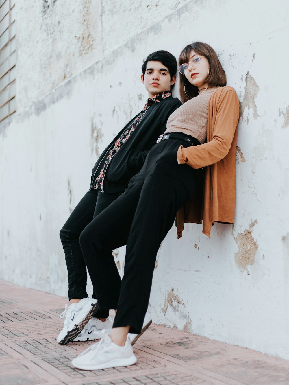 woman in black long sleeve shirt and brown scarf sitting on white concrete wall during daytime