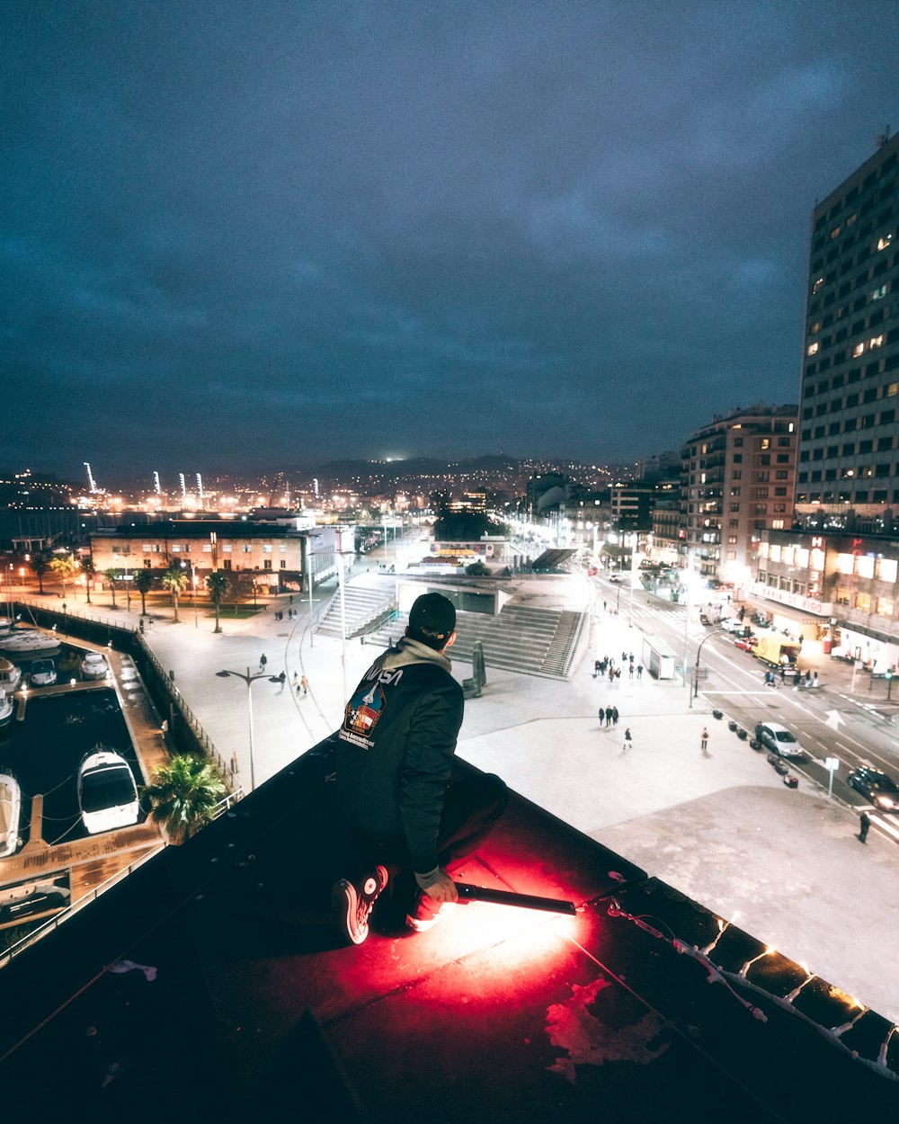 man in black jacket sitting on roof top during night time