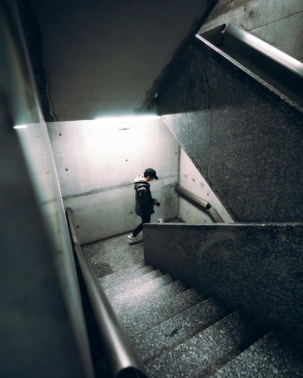 man in black jacket and pants walking on gray concrete stairs