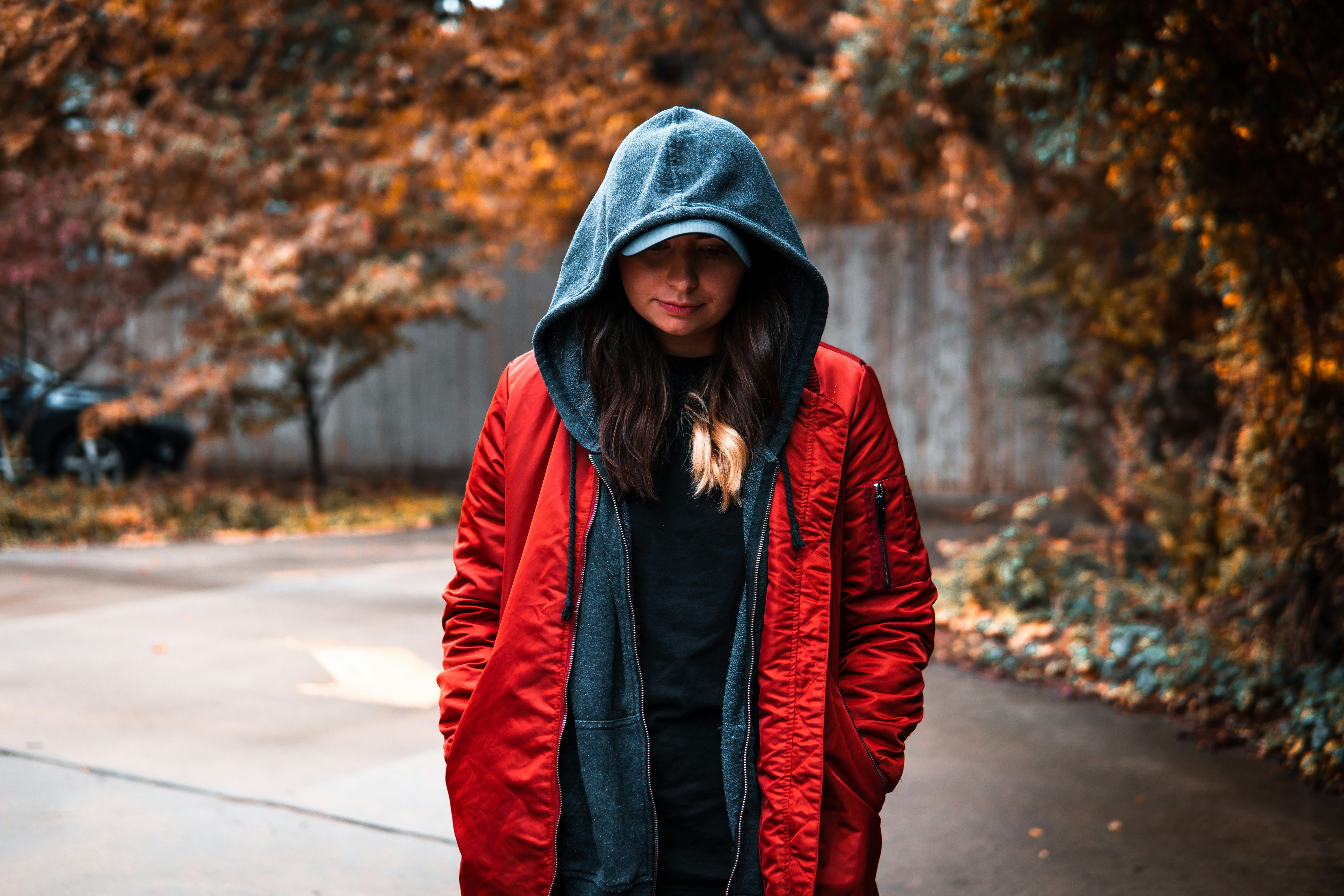 woman in red and black jacket standing on road during daytime