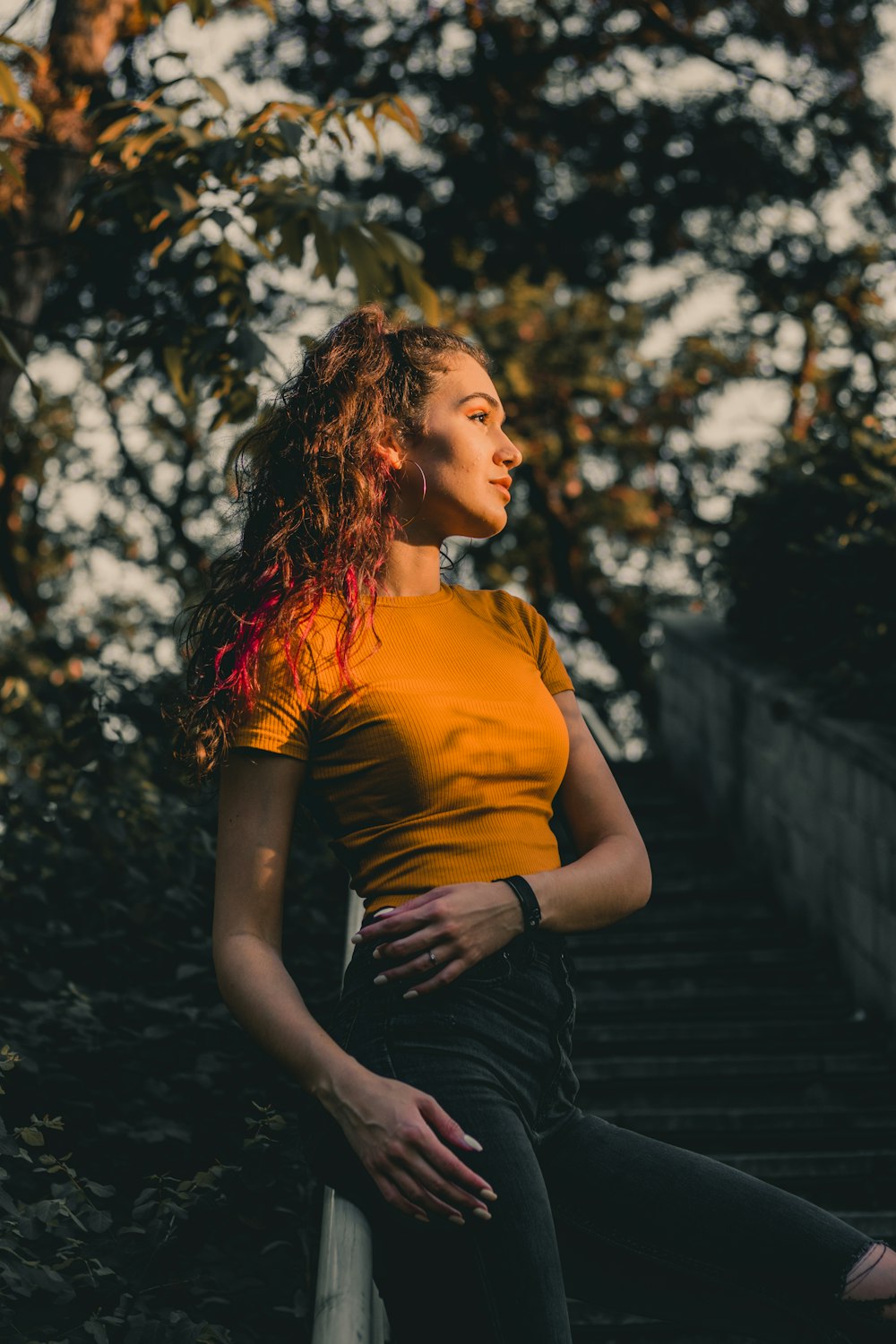 woman in yellow shirt and black skirt sitting on brown wooden bridge