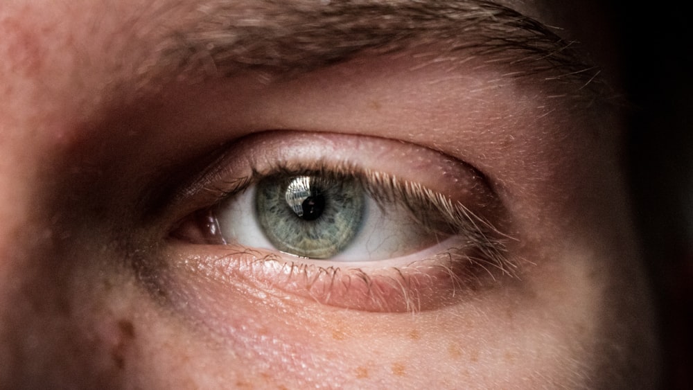 persons blue eye in close up photography