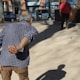 man in black and white checkered button up shirt and brown pants standing on sidewalk during