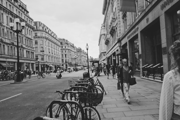 A bustling city street with people using various urban mobility solutions like bikes, scooters, and public transport.