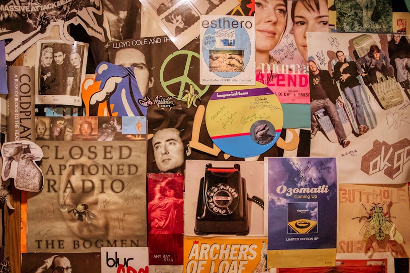 A collage of various music posters and album covers, featuring bands and artists such as Coldplay and OK Go. The image includes handwritten signatures and notes, along with various illustrations and graphics. There's a mix of vibrant and muted tones.