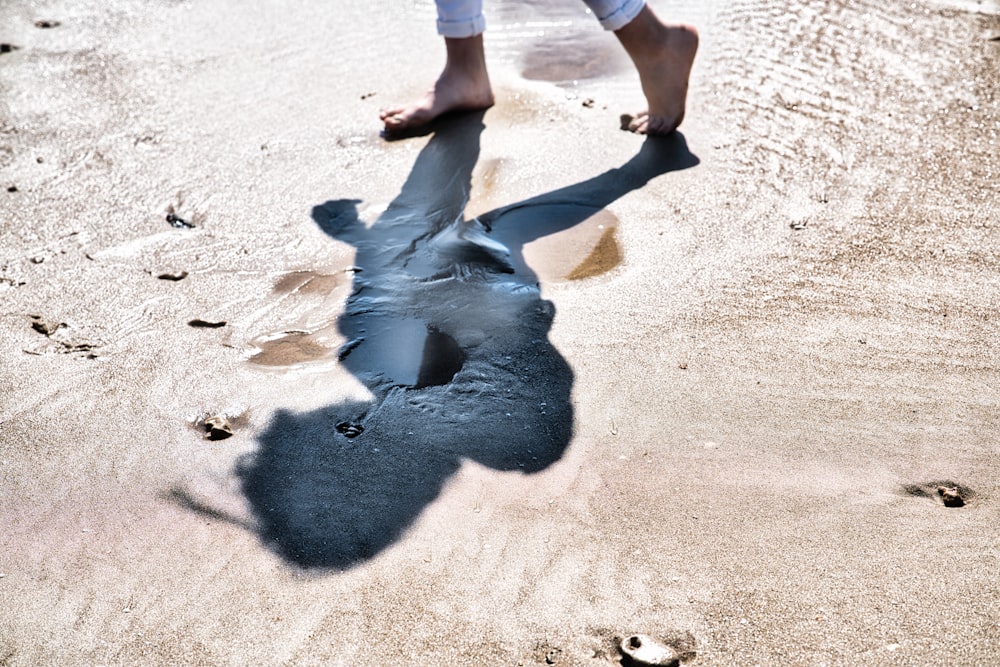 person in black pants walking on white sand during daytime