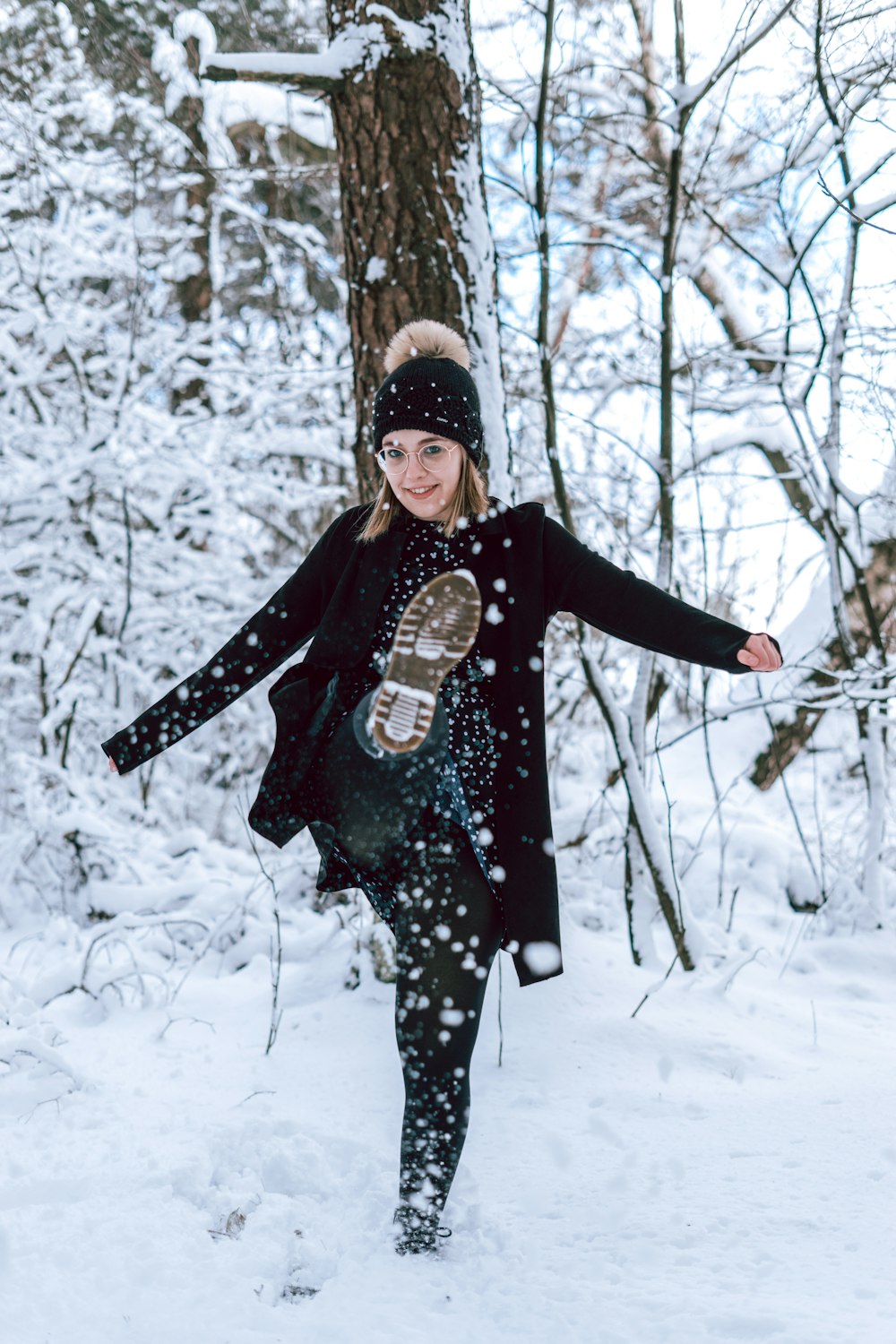 woman in black coat standing on snow covered ground during daytime