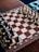 An intricately decorated chessboard with detailed, carved chess pieces set for a game. The board features a combination of light and dark squares with ornate patterns on the borders.