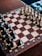 An intricately decorated chessboard with detailed, carved chess pieces set for a game. The board features a combination of light and dark squares with ornate patterns on the borders.