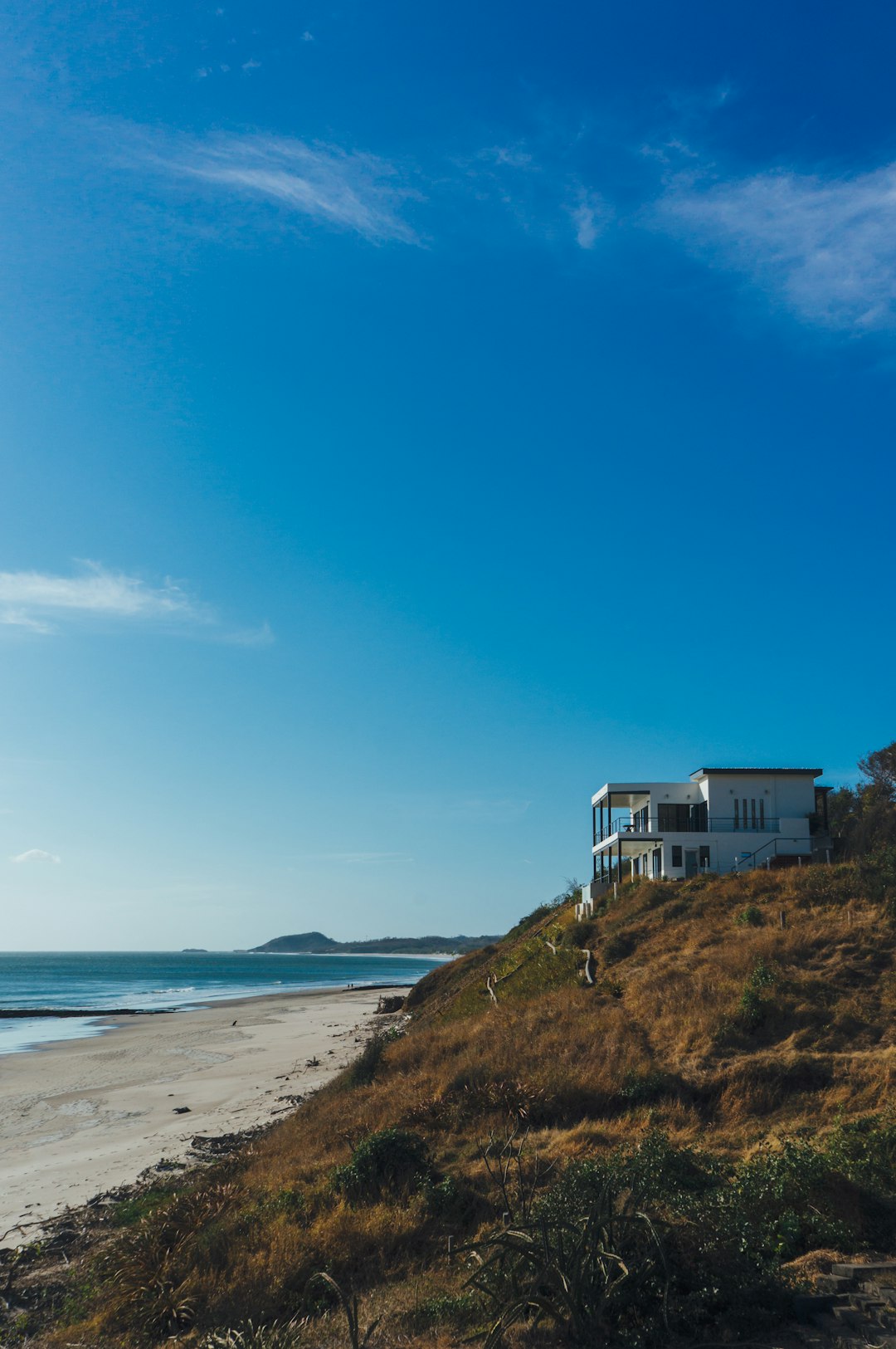 white and blue house on green grass field near body of water under blue sky during