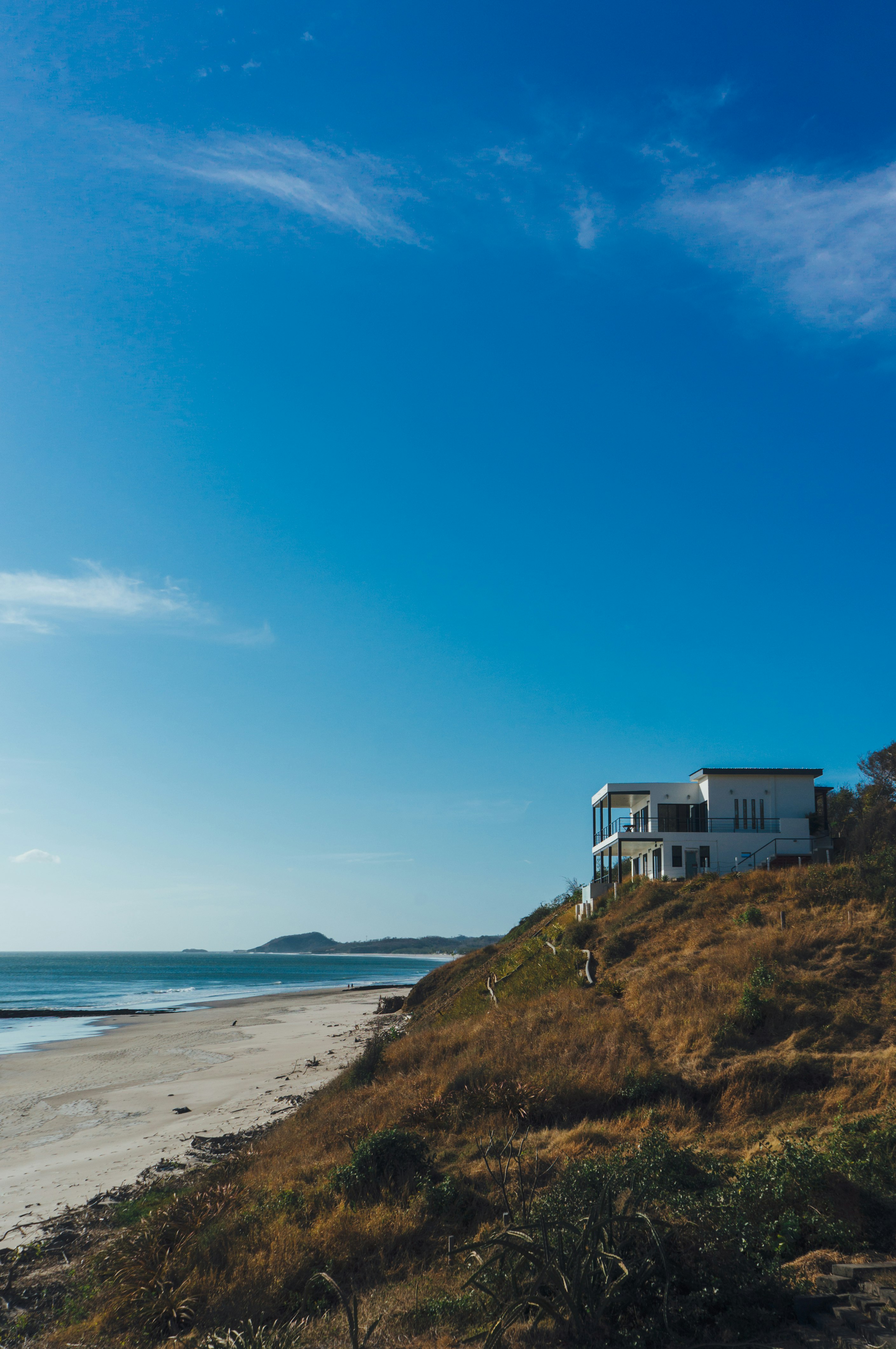 white and blue house on green grass field near body of water under blue sky during