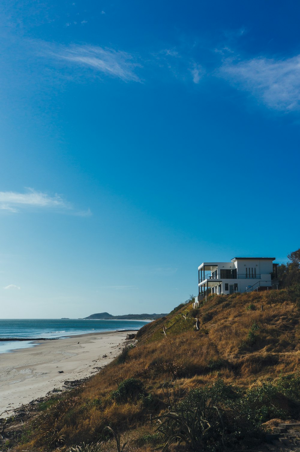 white and blue house on green grass field near body of water under blue sky during