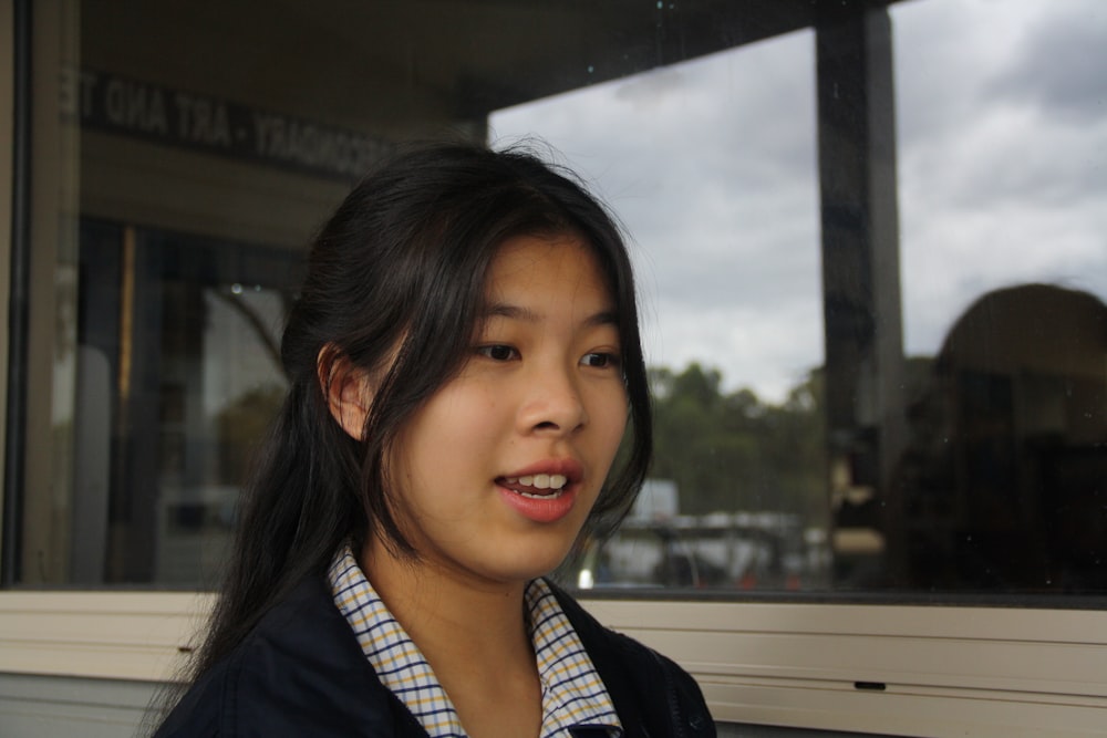 a woman with long black hair and a blue and white checkered shirt