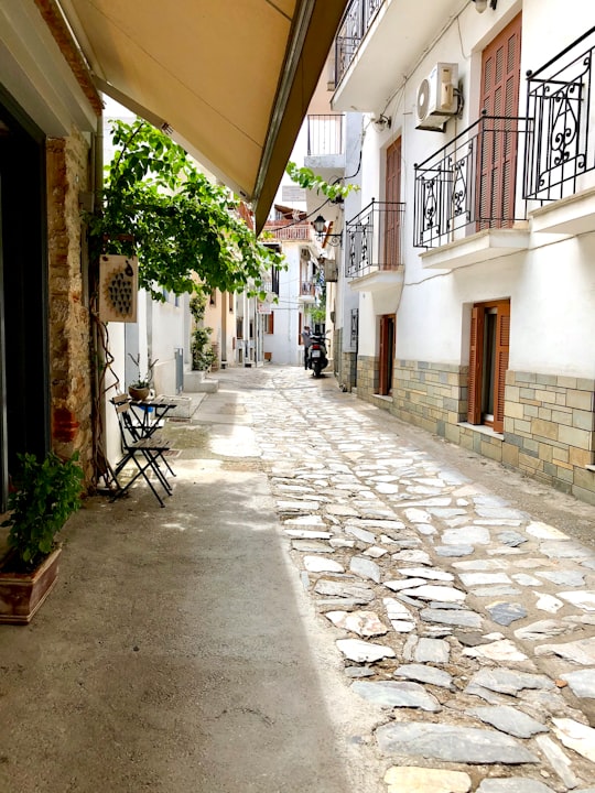 black metal chairs and tables on gray concrete pavement in Skiathos Greece