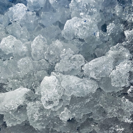 Close-up of a sleek undercounter ice machine with ice cubes spilling out.